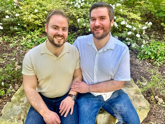 Zack and Mason seated together on a stone bench among white azaleas.