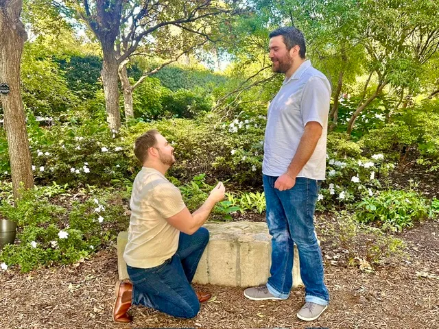 Mason down on one knee in a garden of white azaleas, Zack standing and laughing.