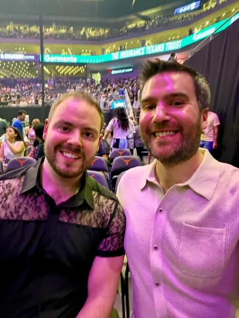 Zack and Mason in a selfie from their seats of Ariana Grande's concert, the arena lit purple behind them.